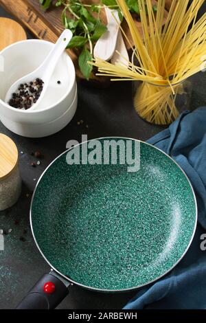 New Empty fry pan with ceramic coatingon on a stone kitchen table surrounded by Italian cuisine ingredients. Stock Photo
