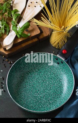 New Empty fry pan with ceramic coatingon on a stone kitchen table surrounded by Italian cuisine ingredients. Stock Photo