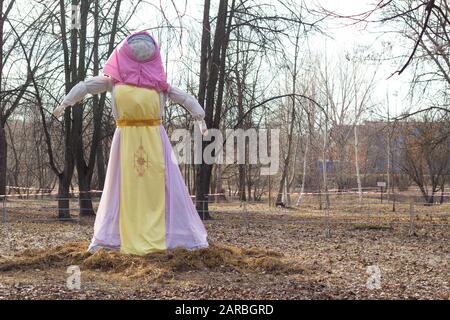 A scarecrow for inflammation by fire stands in nature. The traditional holiday of seeing off winter. Shrovetide Stock Photo