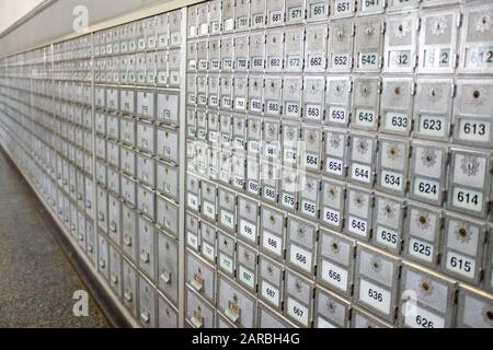 Long wall of grey post office locker boxes of different sizes in perspective selective focus Stock Photo