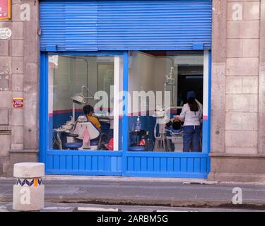 Dental office, with windows giving onto the streets where passerby can view the dentist at work on a patient in chair. Puebla, Mexico Stock Photo