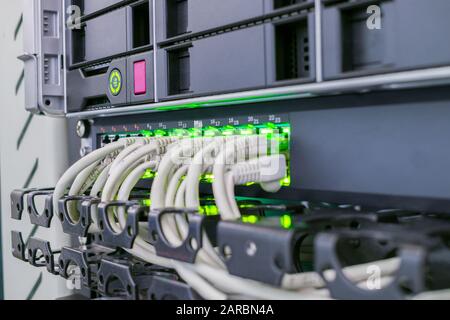 Connecting the Internet wires with computer equipment. Cabling in the server cabinet. The patch panel of the server room of the data center is close u Stock Photo