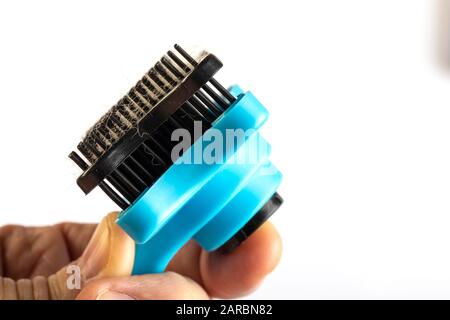 Comb for combing cats and dogs with button for cleaning brush in man hand. Studio Photo on white Stock Photo