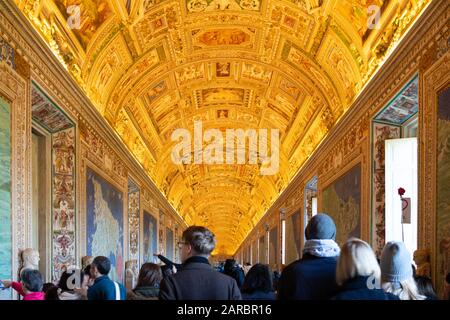 Rome, Italy - Jan 3, 2020: Wall and ceiling paintings in the Gallery of Maps with tourists wandering around at the Vatican Museum, Vatican City, Rome Stock Photo