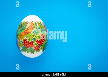 Festive easter greeting card in minimal style. Holiday creative paschal gift card with colorful easter egg. Copy, text space. Blue background, pattern Stock Photo