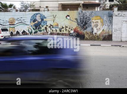 January 27, 2020, Gaza City, The Gaza Strip, Palestine: A Palestinian walks past a drawing of a wall drawn by Palestinian protesters showing the United States Donald J. Trump with a fingerprint on his face in the streets of Gaza City, Gaza Strip, on January 27, 2020 in Gaza City. - Palestinian Prime Minister Muhammad Shtayeh today called on international powers to boycott an American peace plan they see as biased towards Israel, as Israeli Prime Minister Benjamin Netanyahu and his political rival Benny Gantz are scheduled to meet with Donald Trump in Washington, and the American President is e Stock Photo