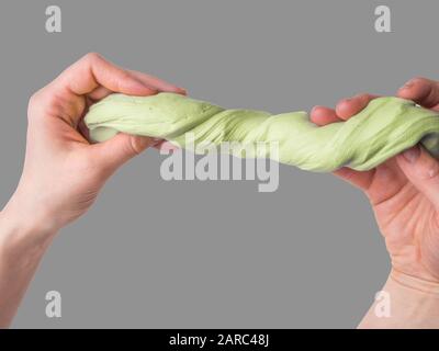 Sticky slime in the hand. The green slime in hands. Favorite toy for a child. Hobby, pleasant to the touch anti-stress trainer Stock Photo