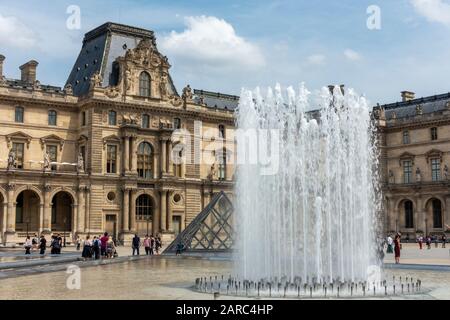 Fountain next to entrance Pyramid on Cour Napoléon (courtyard) with Richelieu Wing in background, Louvre Museum (Musée du Louvre), Paris, France Stock Photo