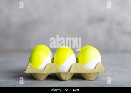 Six yellow painted eggs in tray on a gray concrete background Stock Photo