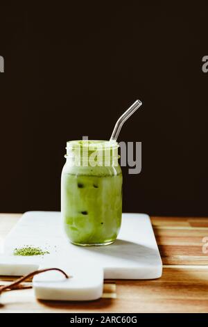 Matcha green tea latte in a glass jar with glass tube on a white marble tray. Healthy clean eating concept. Stock Photo