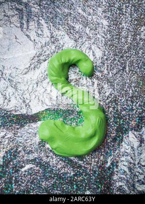 Letter S made from green slime on a aluminium foil shiny surface Stock Photo