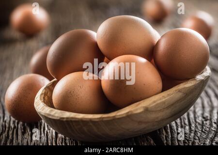 Fresh raw eggs in wooden bowl on rustic wooden table Stock Photo