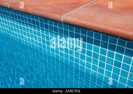 Swimming pool border, mosaic tiles and   terracotta tiled terrace floor - Stock Photo