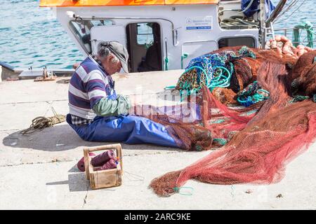 Mending fishing nets on quay, harbour at Sagres, Algarve; Portugal Stock Photo