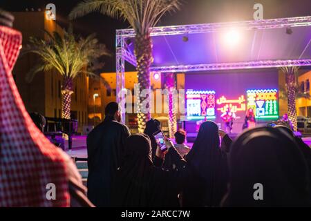 Women in Saudi Arabia filming an outdoor concert at night on their