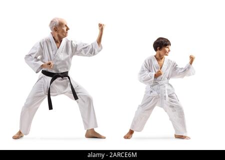Full length shot of a boy and a senior man in kimonos practicing karate isolated on white background Stock Photo