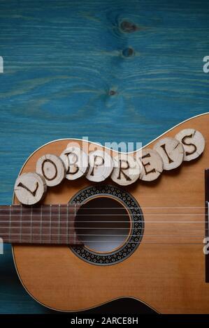 guitar on teal wooden background with wood pieces on it lettering the german word: LOBPREIS Stock Photo