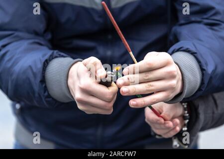 Closeup shot of a person lighting up a Bengali fire with a lighter in his hands Stock Photo