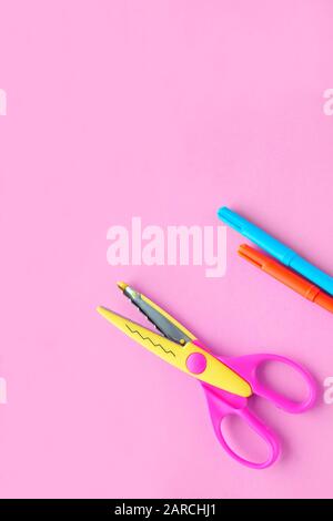 scissors, ruler and crayons on a pink vertical background. Creative, fashionable, minimalistic, school or office workspace with yellow supplies for Stock Photo
