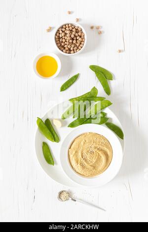 Homemade chickpea hummus served with green peas, healthy vegetarian food concept, top view Stock Photo