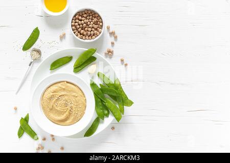 Homemade chickpea hummus served with green peas, healthy vegetarian food concept, top view Stock Photo