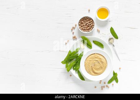 Homemade chickpea hummus served with green peas, healthy vegetarian food concept, top view Stock Photo