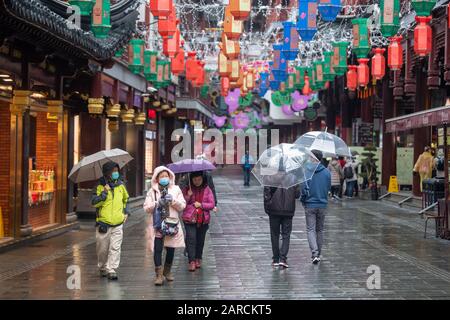 Shanghai, China, 25th Jan 2020, People wearing masks use umbrellas as they walk down the empty streets Stock Photo