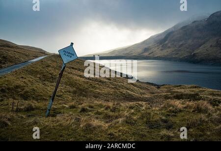 Passing place sign with Lochan na Lairige water reservoir in the background in Scottish Highlands.