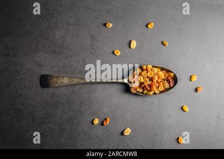 Dried raisins on a spoon over black marble background Stock Photo