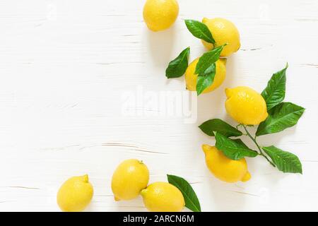 Fresh lemons with leaves on white wooden background,  summer lemonade ingredient, vitamin c concept, top view Stock Photo