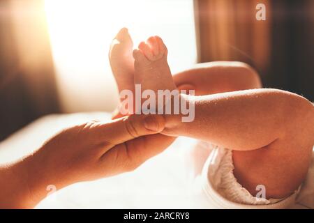Baby feet in mother hands. Tiny Newborn Baby's feet on female Shaped hands closeup. Mom and her Child. Happy Family concept. Beautiful conceptual image of Maternity Stock Photo