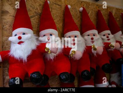 plush figurines of Santa Claus with bells on a street stand Stock Photo