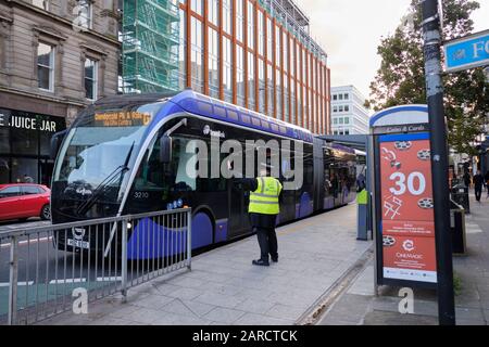 Glider transit,  Van Hool ExquiCity 18 vehicle in centre of Belfast stop. Driver waiting for instruction from coordinator Stock Photo