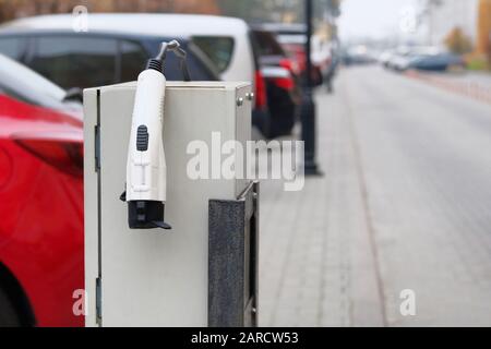 Electric vehicle charger station installed in parking lot in modern residential area. Eco friendly transport concept. Close up. Stock Photo