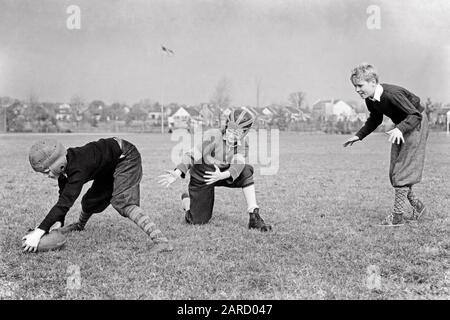 1940s THREE BOYS PLAYING FOOTBALL - b12595 HAR001 HARS KNICKERS JOY LIFESTYLE STUDIO SHOT HEALTHINESS ATHLETICS NATURE COPY SPACE FRIENDSHIP FULL-LENGTH INSPIRATION MALES ATHLETIC SERENITY CONFIDENCE B&W ACTIVITY DREAMS PHYSICAL HIGH ANGLE LEISURE STRENGTH STRATEGY RECREATION FALL SEASON PRIDE SWEATERS CONNECTION CONCEPTUAL ATHLETES FLEXIBILITY FRIENDLY MUSCLES STYLISH HELMETS COOPERATION FOOTBALLS GROWTH JUVENILES TOGETHERNESS AMERICAN FOOTBALL AUTUMNAL BLACK AND WHITE CAUCASIAN ETHNICITY FALL FOLIAGE HAR001 OLD FASHIONED Stock Photo