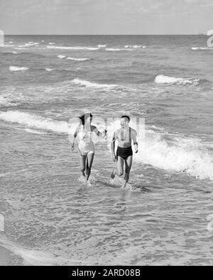 1930s 1940s VACATION COUPLE WEARING BATHING SUITS PLAYING IN SURF AT BEACH  WOMAN RUNNING TOWARD SMILING MAN FLORIDA USA - b7126 HAR001 HARS 1 FITNESS  SILLY TROPICAL HEALTHY COMIC VACATION STRONG JOY