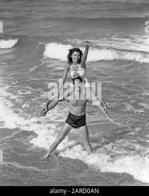 1930s 1940s VACATION COUPLE WEARING BATHING SUITS PLAYING IN SURF AT BEACH  WOMAN RUNNING TOWARD SMILING MAN FLORIDA USA - b7126 HAR001 HARS 1 FITNESS  SILLY TROPICAL HEALTHY COMIC VACATION STRONG JOY
