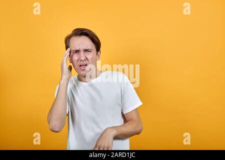The young husband holds his hand on head wincing in pain. Stock Photo