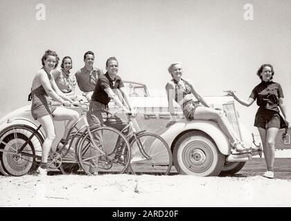 1930s GROUP OF MEN AND WOMEN WEARING BATHING SUITS CASUAL CLOTHES ON BICYCLES IN A CAR ON BEACH ALL LOOKING AT CAMERA SMILING  - m5585 HAR001 HARS 6 COPY SPACE FRIENDSHIP FULL-LENGTH HALF-LENGTH LADIES PERSONS AUTOMOBILE MALES SIX CONFIDENCE BICYCLES TRANSPORTATION B&W BIKES SUMMERTIME EYE CONTACT SHORE HAPPINESS CHEERFUL LEISURE AND AUTOS LOW ANGLE RECREATION BEACHES SMILES CONNECTION AUTOMOBILES JOYFUL SANDY STYLISH VEHICLES COOPERATION MID-ADULT MID-ADULT MAN SEASON TOGETHERNESS YOUNG ADULT MAN YOUNG ADULT WOMAN BLACK AND WHITE CASUAL CAUCASIAN ETHNICITY HAR001 OLD FASHIONED Stock Photo