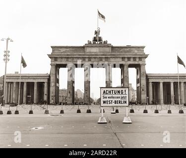 1960s BRANDENBURG GATE LOOKING TOWARD EAST BERLIN FROM WEST SIGN SAYS ATTENTION YOU ARE NOW LEAVING WEST BERLIN COLD WAR ERA - r17272 BAU001 HARS COLD WAR ARE NEOCLASSICAL AUTHORITY NOW POLITICS CONCEPT CONCEPTUAL ESCAPE SYMBOLIC BRANDENBURG BUILT CONCEPTS PRECISION SAYS TOGETHERNESS 18TH CENTURY BLACK AND WHITE ERA LANDMARK OLD FASHIONED REPRESENTATION Stock Photo