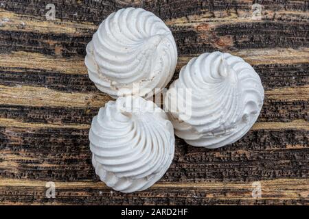 White, whipped, gray and pink swirl meringue cake named Pavlova in the preparation process. White, gray and pink beze swirls on wooden table. Stock Photo