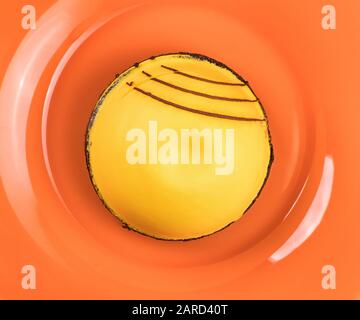 Yellow round cake on the orange plate close up. Top view Stock Photo