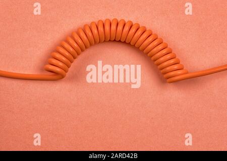 Orange spiral cable on orange background. Abstract communication and connection theme still life Stock Photo
