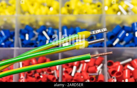 Insulated cord pin end terminals on green electric conductors detail. Stripped copper wire or yellow crimped power cable connectors. Assorted ferrules. Stock Photo