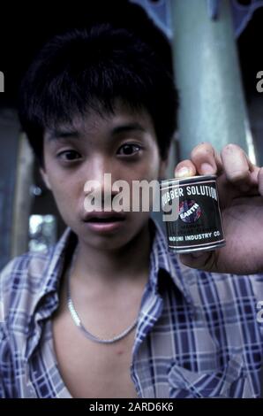 YOUNG MAN IN SINGAPORE GLUE SNIFFING. ALSO KNOWN AS BAGGING, GLADING, DUSTING OR HUFFING. Stock Photo