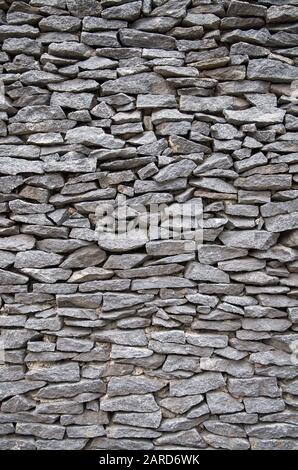 Full frame vertical close-up of flat gray stones stacked tightly in a wall Stock Photo