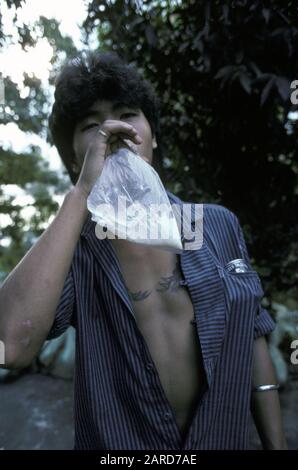 YOUNG MAN IN SINGAPORE GLUE SNIFFING. ALSO KNOWN AS BAGGING, GLADING, DUSTING OR HUFFING. Stock Photo