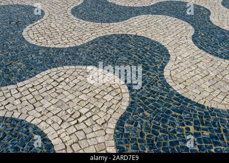 Traditional cobblestone design in Portugal, black & white cobbles making a wave design in stones. Stock Photo
