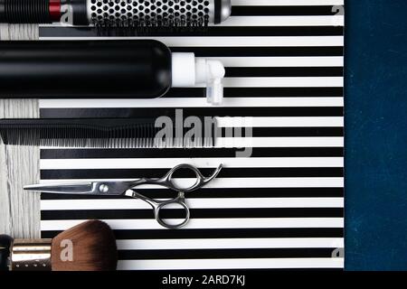 Haircut machines, nozzles of different sizes, combs and gels for styling, laid out on a beautiful black white striped background which stands on a blu Stock Photo
