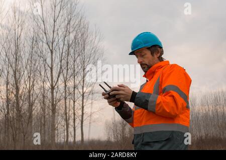 Forestry technician flying a drone with remote controller in woods and making aerial photos of forest Stock Photo